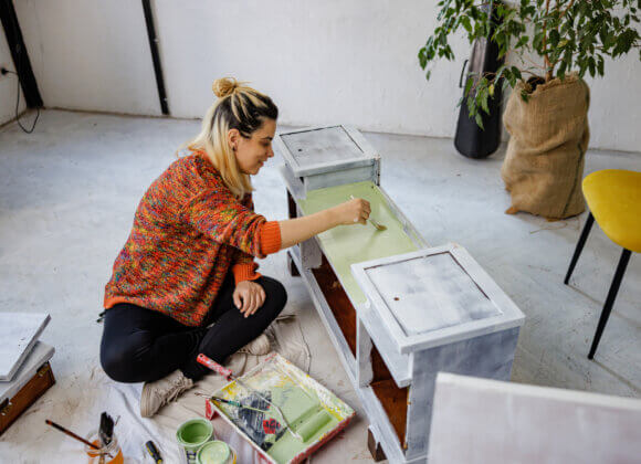 Счастливая женщина красит старую мебель