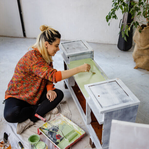 Happy lady painting old furniture