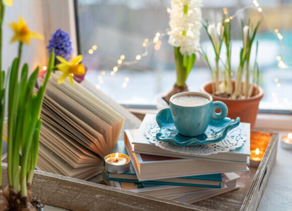 Кофейная чашка, открытая книга, красивые цветы, свечи на победе