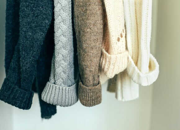 Вязаная одежда джемперы висит в шкафу. Осенне-зимний гардероб