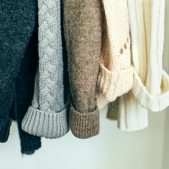 Knitted clothes sweater hanging in the closet. ?ozy autumn-winter wardrobe