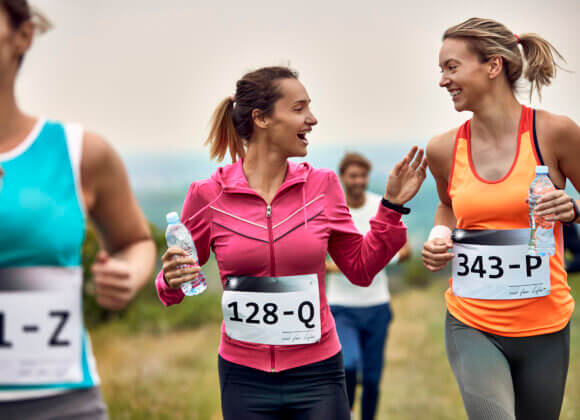 Счастливые женщины-бегуньи общаются во время марафона на природе.