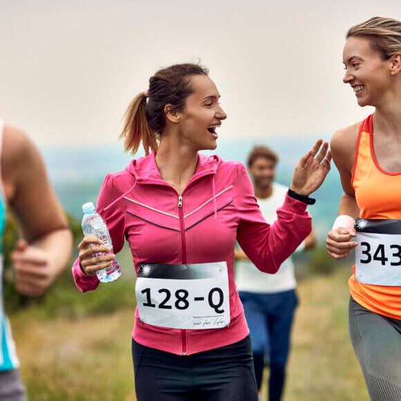 Happy female runners communicating while participating in marathon in nature.