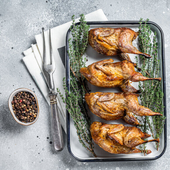 Homemade sticky Roast quails with spices and herbs in a baking d