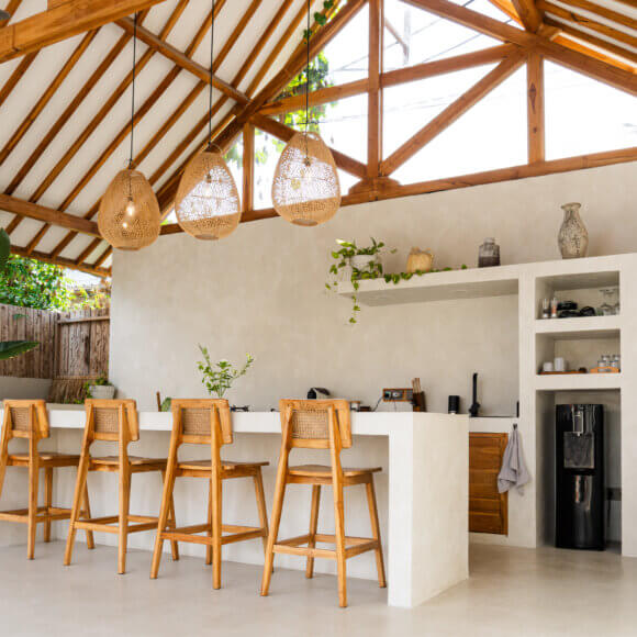 Cuisine minimaliste ouverte, avec des tabourets de bar en bois et des suspensions en rotin, dans une villa tropicale