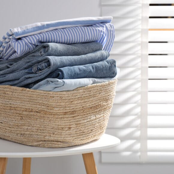 Panier à linge rempli de vêtements posé sur une table à l'intérieur