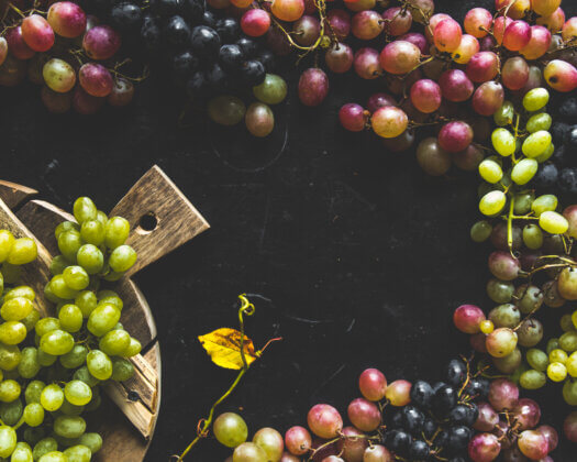 Assortment of fresh grape on cutting board. Grey wooden background.