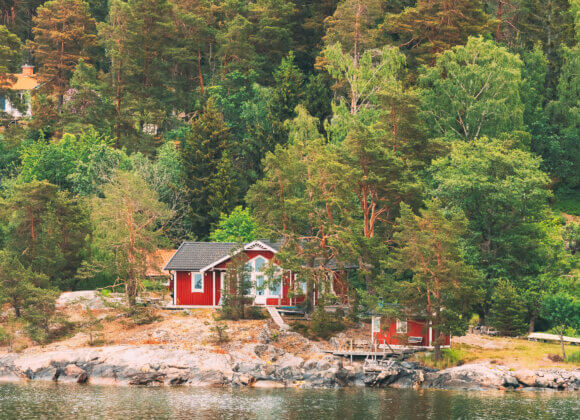 Sweden. Beautiful red Swedish wooden log cabins on the rocky island coast in summer. Lake or river landscape