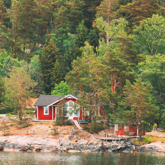 Suède. De magnifiques chalets suédois en rondins rouges sur la côte rocheuse de l'île en été. Paysage de lac ou de rivière